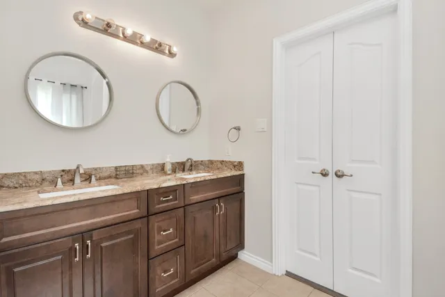 a bathroom with a granite countertop double vanity sink and a mirror