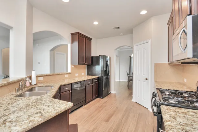 a large kitchen with stainless steel appliances granite countertop a sink stove and refrigerator