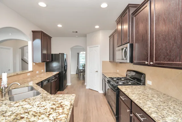 a kitchen with granite countertop a sink stove and refrigerator