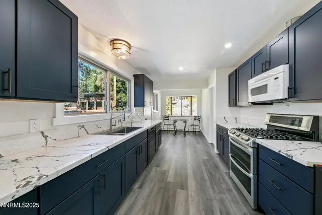 a kitchen with granite countertop stainless steel appliances a sink dishwasher a stove top oven a refrigerator with wooden floors