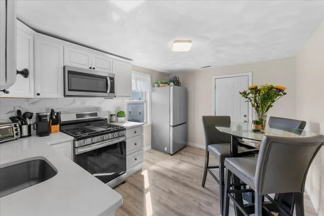 a kitchen with stainless steel appliances a stove a table chairs and a refrigerator