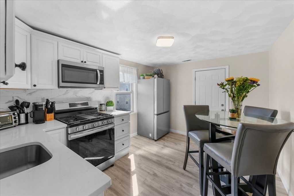 49 A Massasoit Avenue, Unit 2 Hull, MA 02045 - Photo 2 of 19 a kitchen with stainless steel appliances a stove a table chairs and a refrigerator