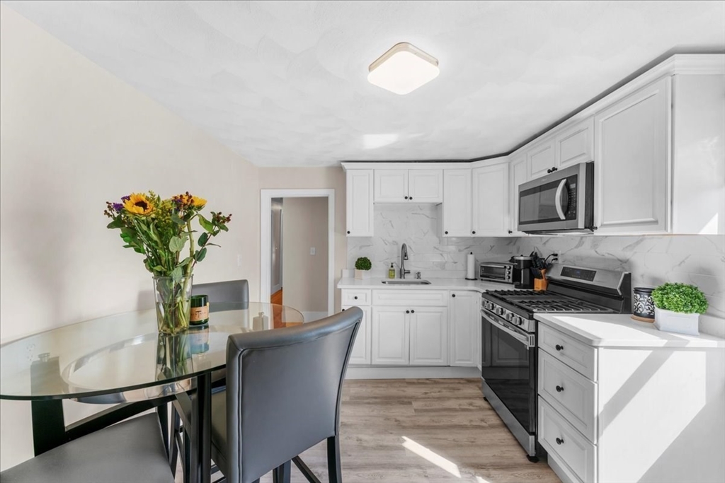 49 A Massasoit Avenue, Unit 2 Hull, MA 02045 - Photo 3 of 19 a kitchen with stainless steel appliances a stove a sink a microwave cabinets and a dining table