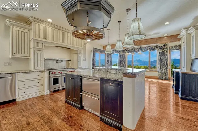 a kitchen with stainless steel appliances kitchen island granite countertop a stove refrigerator and cabinets