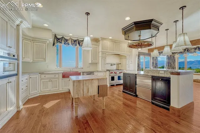 a kitchen with stainless steel appliances granite countertop a sink a stove and a wooden floors