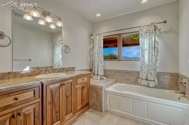 a bathroom with a granite countertop sink a large mirror and a bathtub
