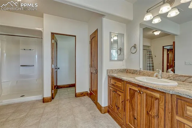 a spacious bathroom with a granite countertop sink a mirror and a shower
