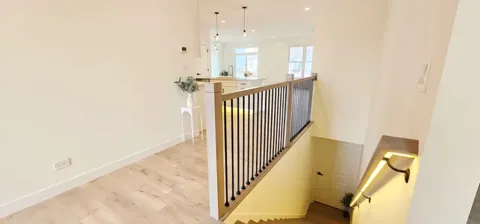 a view of a hallway with wooden floor and staircase