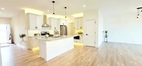 a large white kitchen with wooden floor