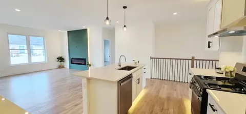 a kitchen that has a sink a stove and wooden floor