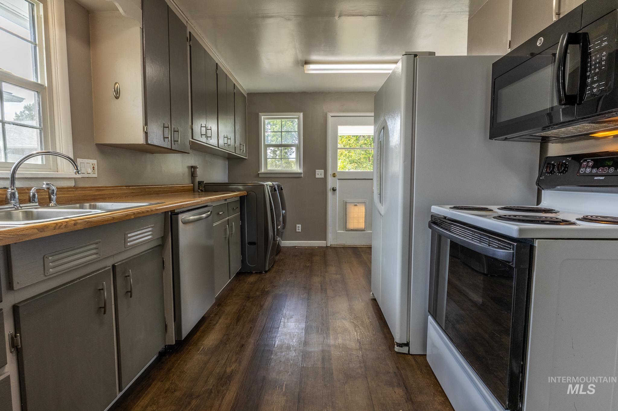 3228 5th Street Lewiston, ID 83501 - Photo 14 of 24 Kitchen with white electric stove, black microwave, dark wood-style flooring, stainless steel dishwasher, and gray cabinets