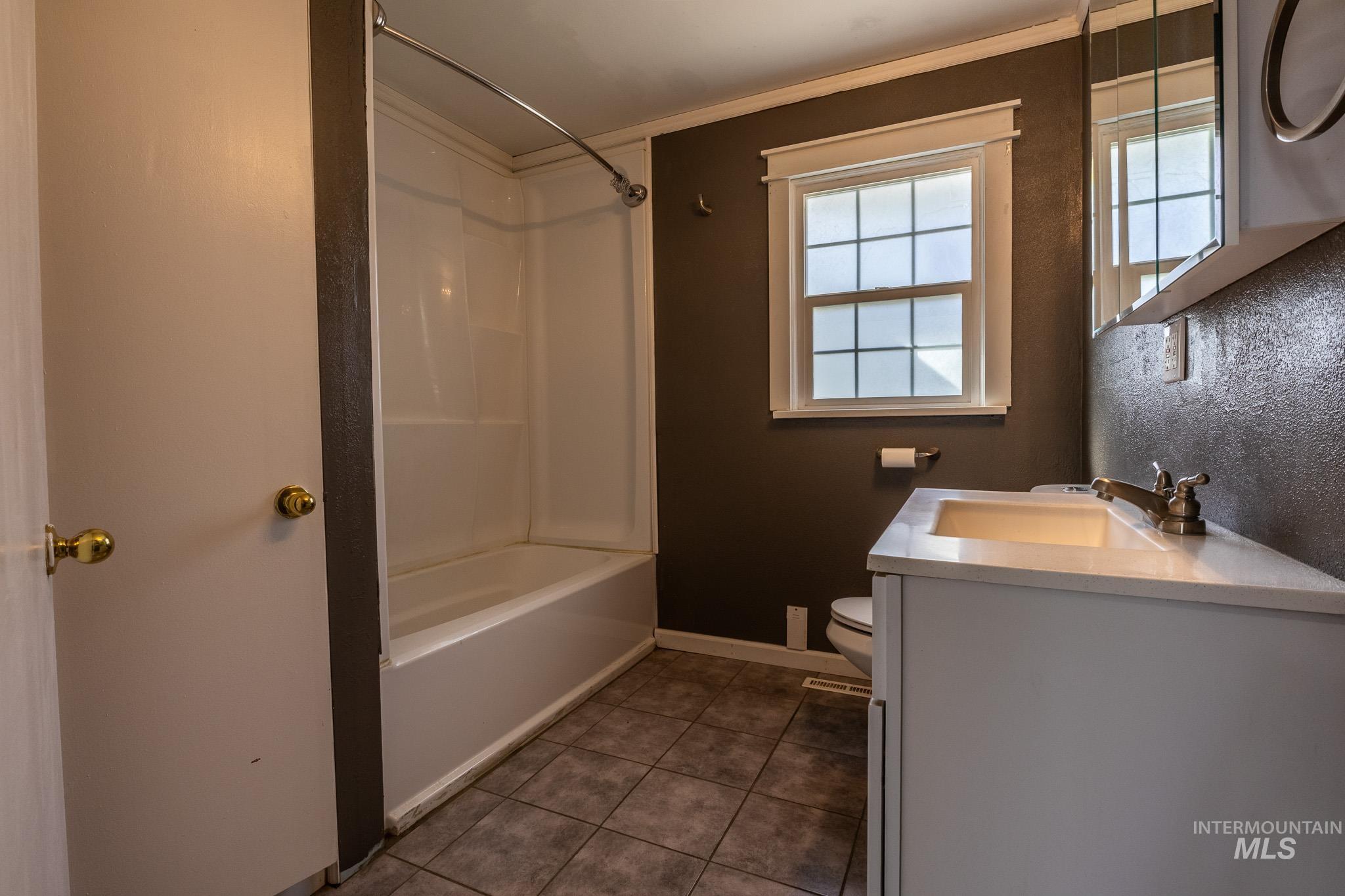 3228 5th Street Lewiston, ID 83501 - Photo 8 of 24 Bathroom with shower / tub combination, vanity, dark tile patterned floors, and ornamental molding