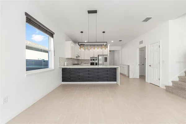 a large white kitchen with granite countertop a stove top oven a sink a counter space and cabinets