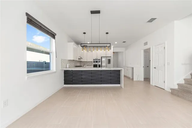 a large white kitchen with granite countertop a stove top oven a sink a counter space and cabinets
