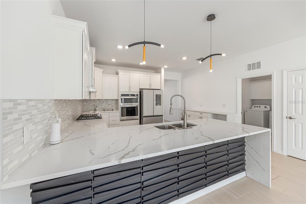 6366 Southwest 77th Avenue Ocala, FL 34474 - Photo 38 of 65 a kitchen with kitchen island a sink stainless steel appliances and a chandelier