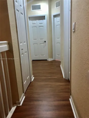a view of a hallway with wooden floor and staircase