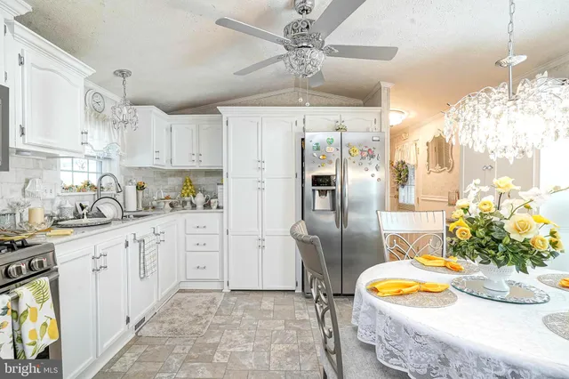 a kitchen with stainless steel appliances granite countertop a refrigerator a sink a stove and white cabinets