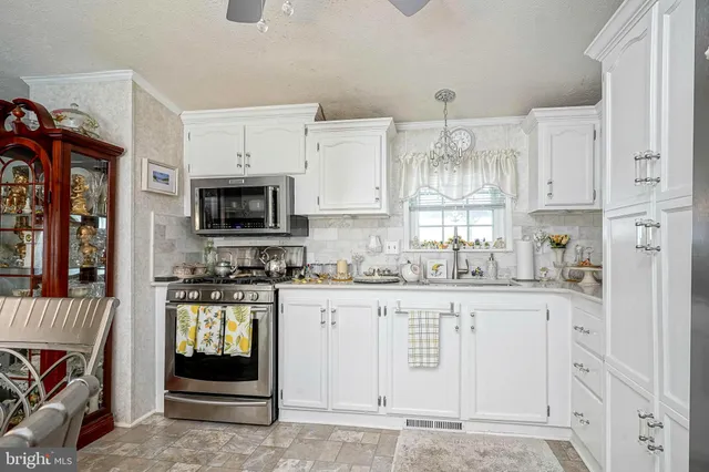 a kitchen with granite countertop a stove top oven a sink dishwasher and a microwave oven with white cabinets