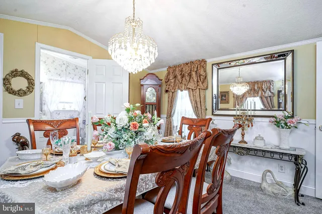a view of a dining room with furniture a chandelier and window