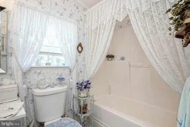 a white bath tub sitting next to a white toilet and curtain