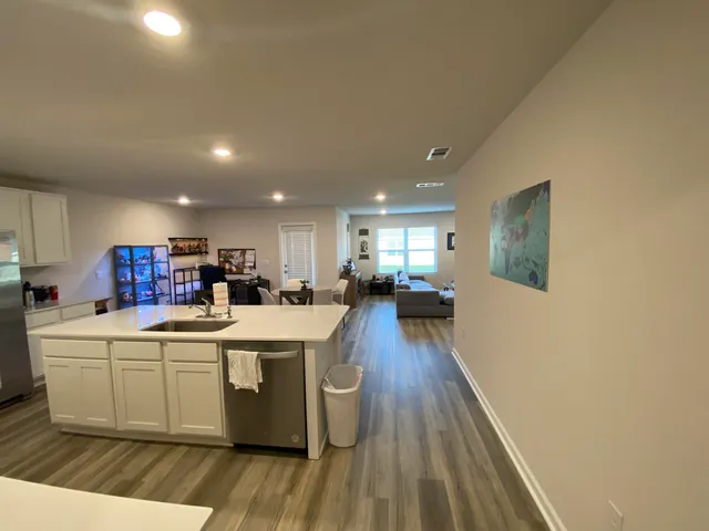 a living room with stainless steel appliances kitchen island granite countertop furniture wooden floor and a view of kitchen