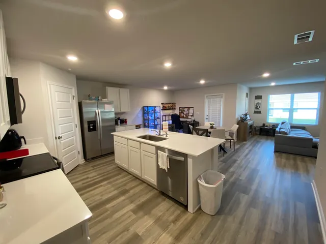 a large kitchen with stainless steel appliances a large counter top a sink a refrigerator and a stove