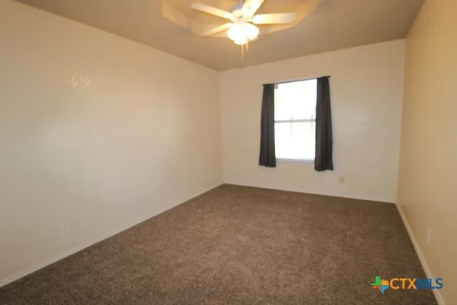an empty room with a window and a ceiling fan
