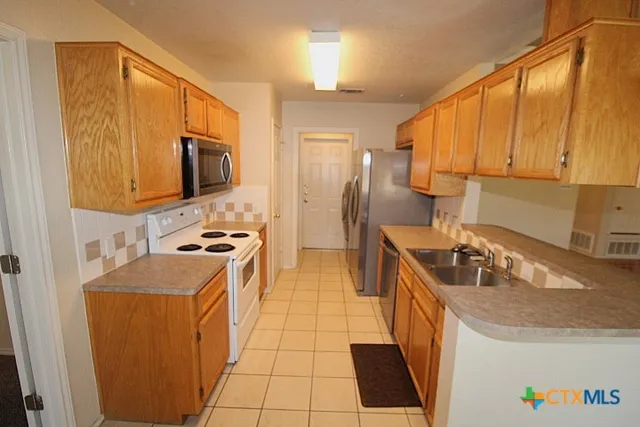 a kitchen with stainless steel appliances granite countertop a sink a stove and a refrigerator