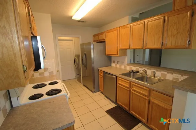 a kitchen with stainless steel appliances a sink a stove a refrigerator and cabinets