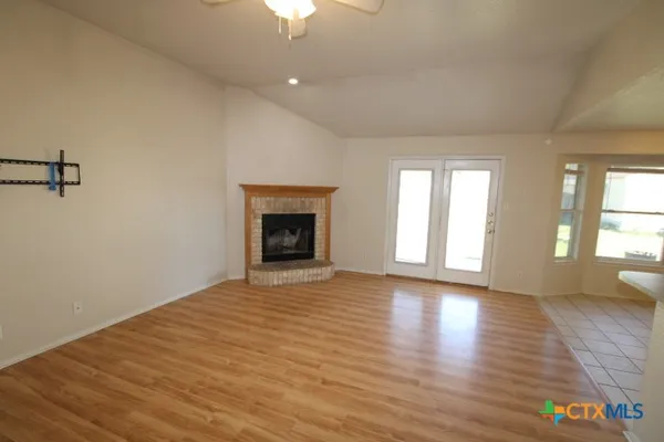 a view of an empty room with a window and wooden floor