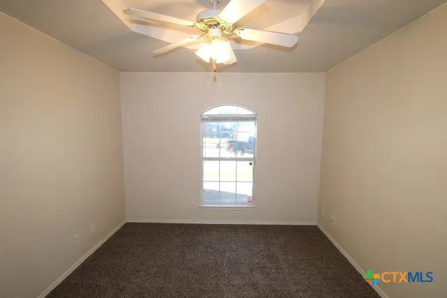 an empty room with a window and a fan