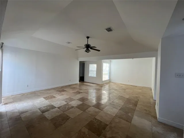 a view of an empty room with window and ceiling fan