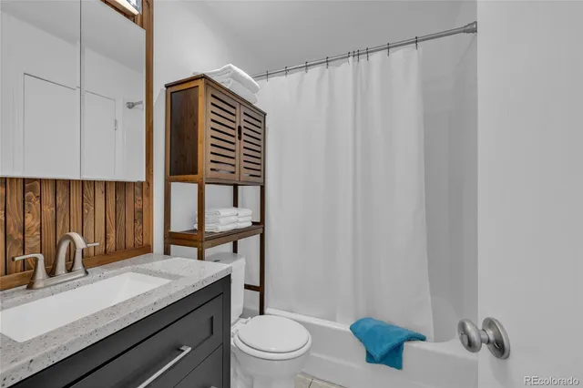 a bathroom with a granite countertop sink a toilet and shower