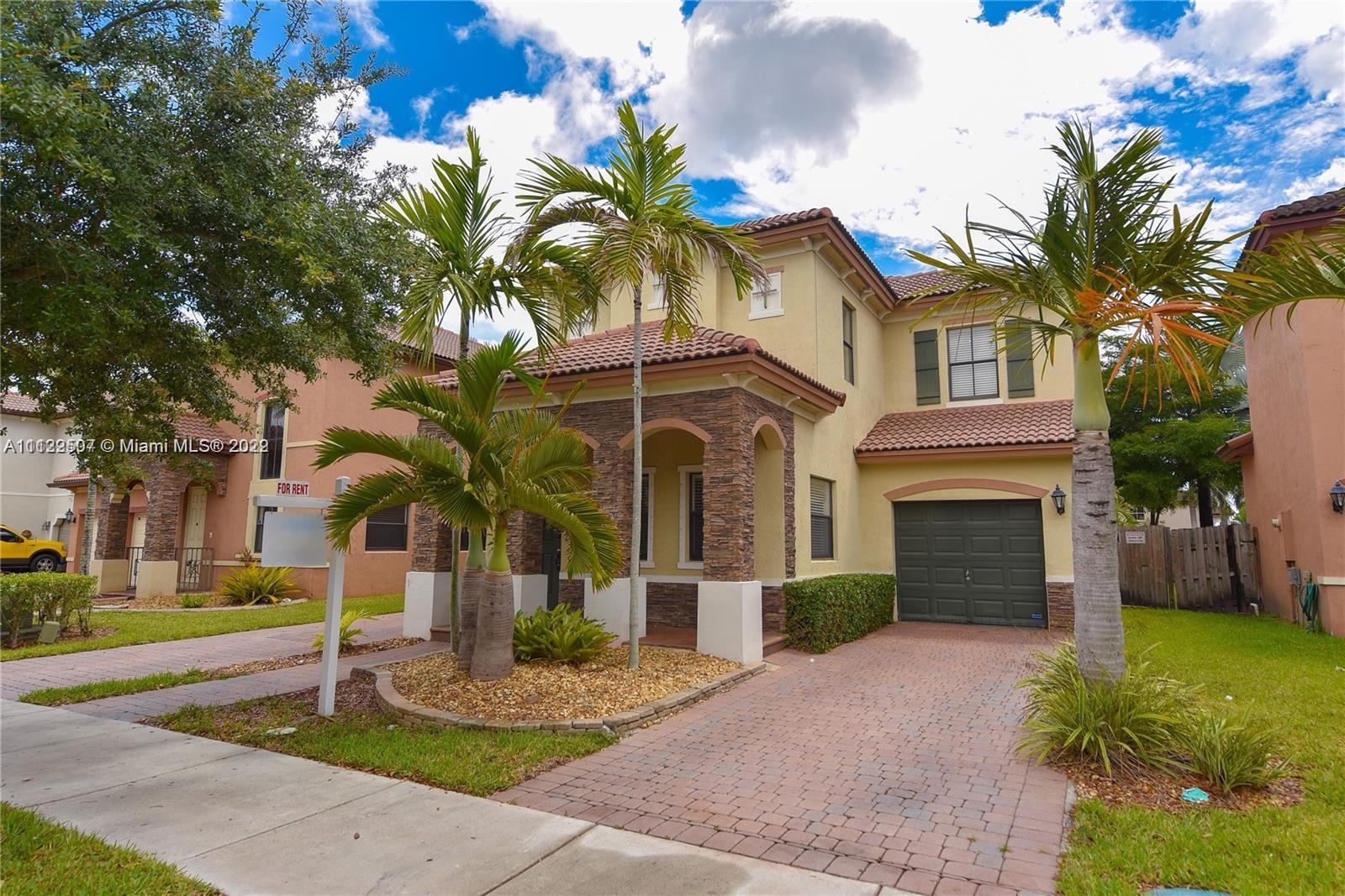 24221 Southwest 112th Court Homestead, FL 33032 - Photo 2 of 25 a front view of a house with a garden and trees