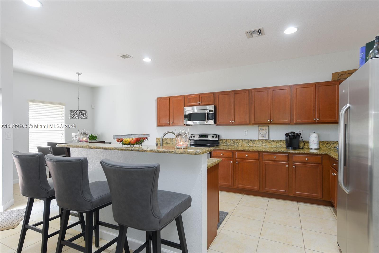 24221 Southwest 112th Court Homestead, FL 33032 - Photo 6 of 25 a kitchen with a dining table chairs and refrigerator