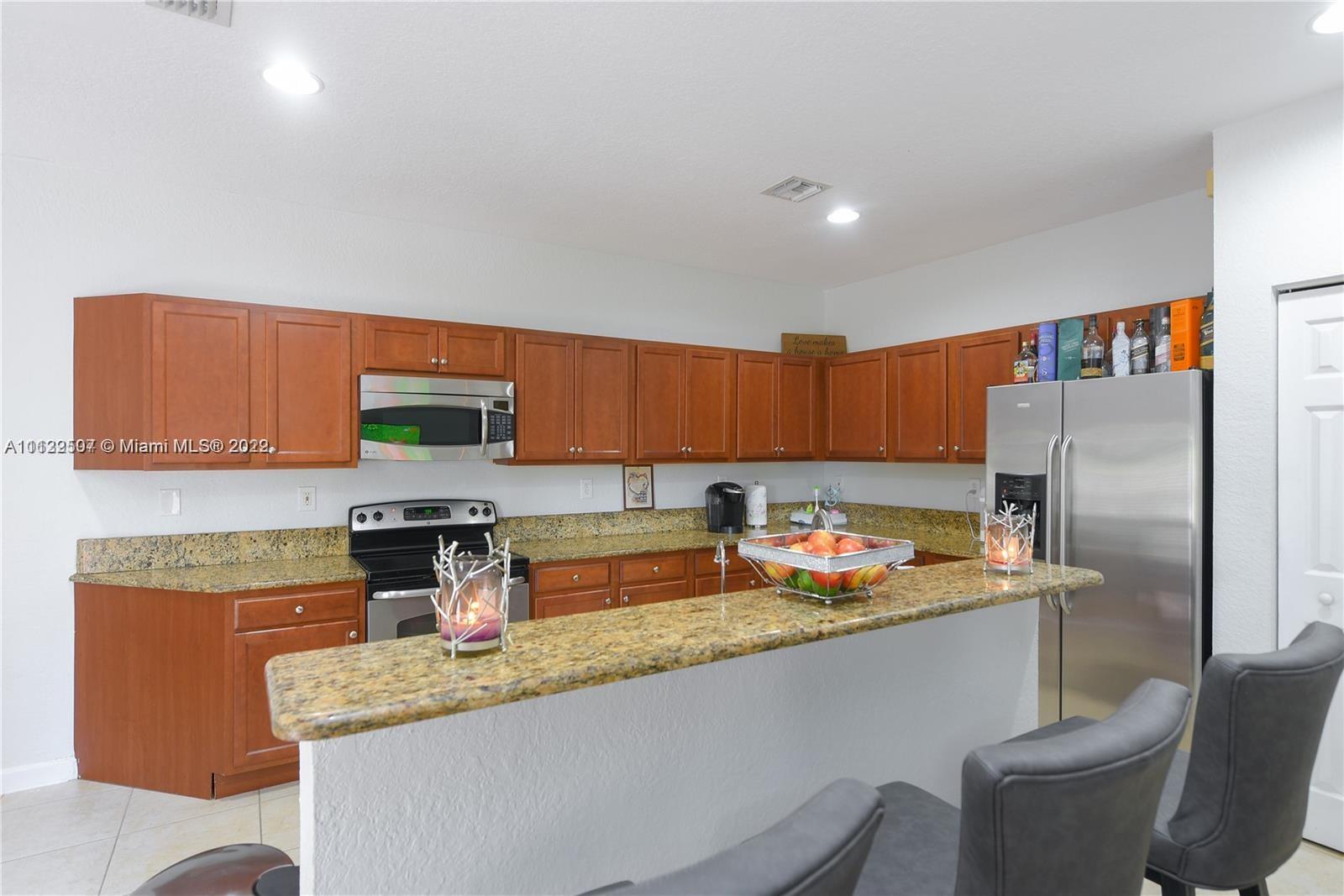 24221 Southwest 112th Court Homestead, FL 33032 - Photo 7 of 25 a kitchen with stainless steel appliances granite countertop a sink refrigerator and cabinets
