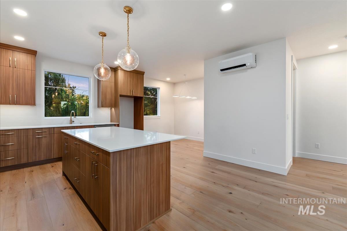 3213 West Moore Street Boise, ID 83702 - Photo 14 of 32 Kitchen featuring an expansive island with a white countertop, wood-finish cabinetry, light wood-finish flooring, recessed lighting, and a ductless mini-split system