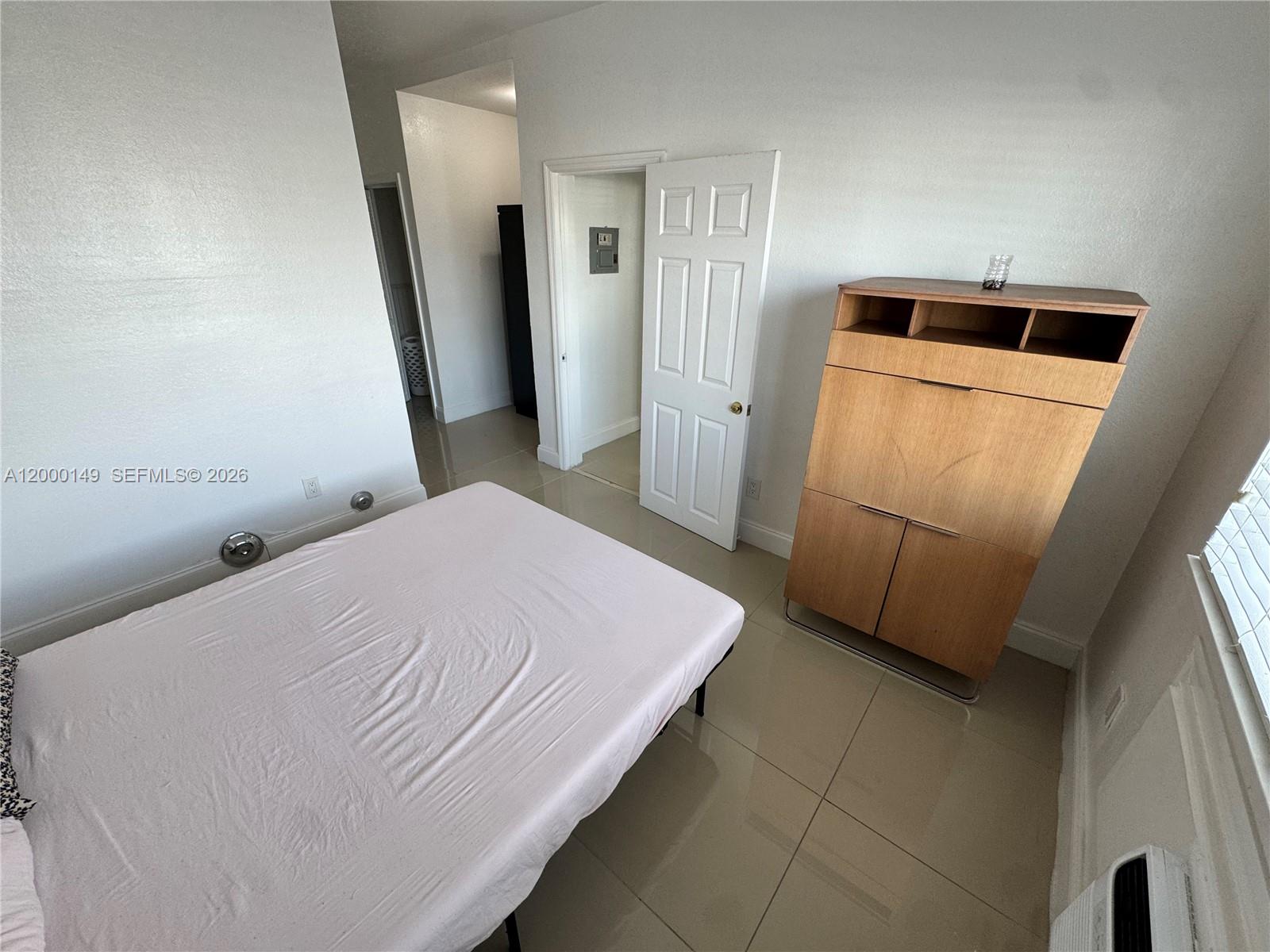 8415 Harding Avenue, Unit 9 Miami Beach, FL 33141 - Photo 14 of 14 a bedroom with a bed and a refrigerator