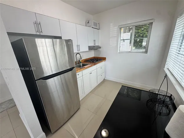 a kitchen with granite countertop a refrigerator a sink a stove and cabinets