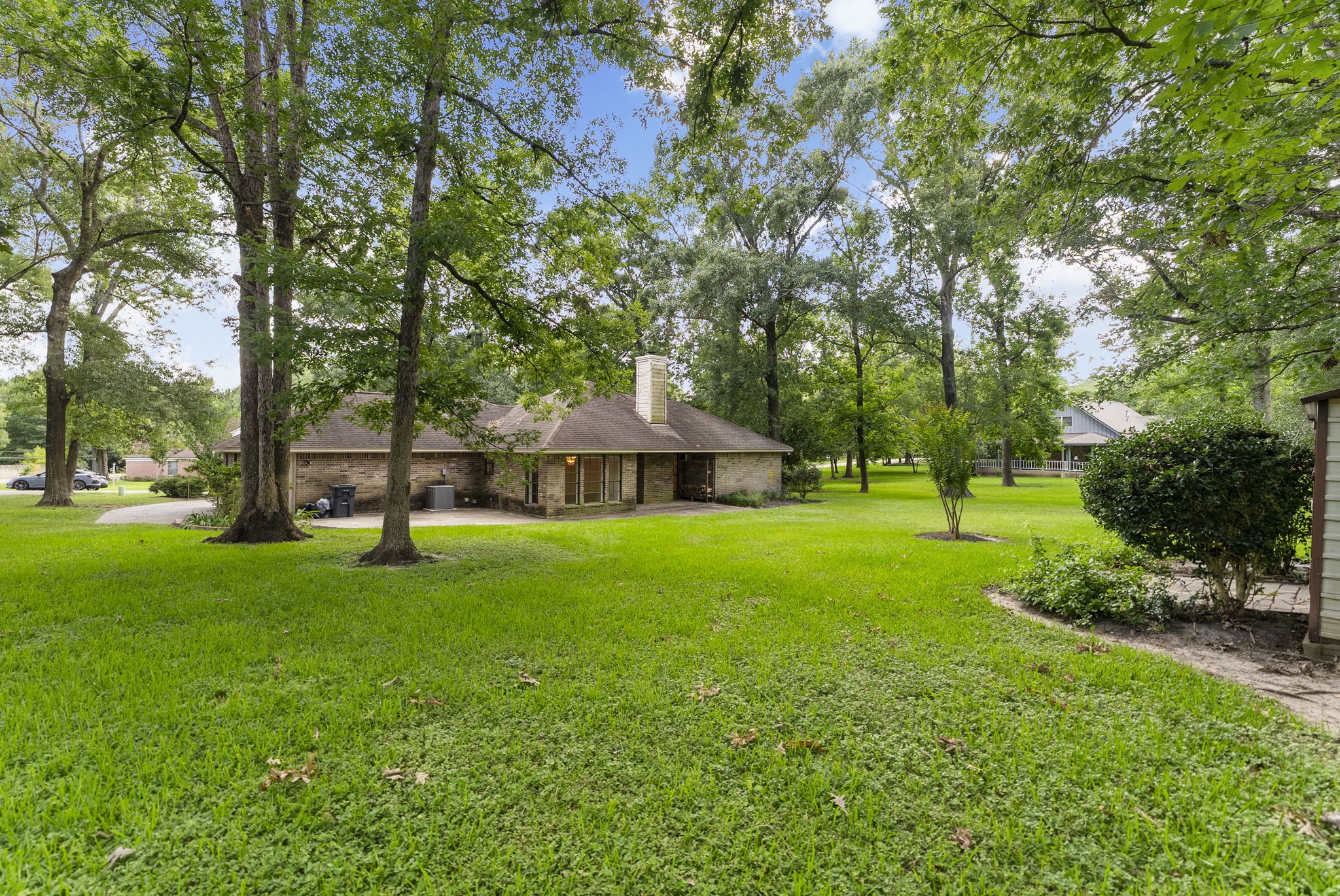 202 Sunset Boulevard Conroe, TX 77303 - Photo 38 of 50 Spacious backyard with lush greenery and mature trees, featuring a charming single-story brick home. Ideal for nature lovers seeking privacy and tranquility.