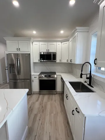 a kitchen with kitchen island a sink stainless steel appliances and cabinets