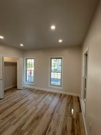 an empty room with wooden floor and windows