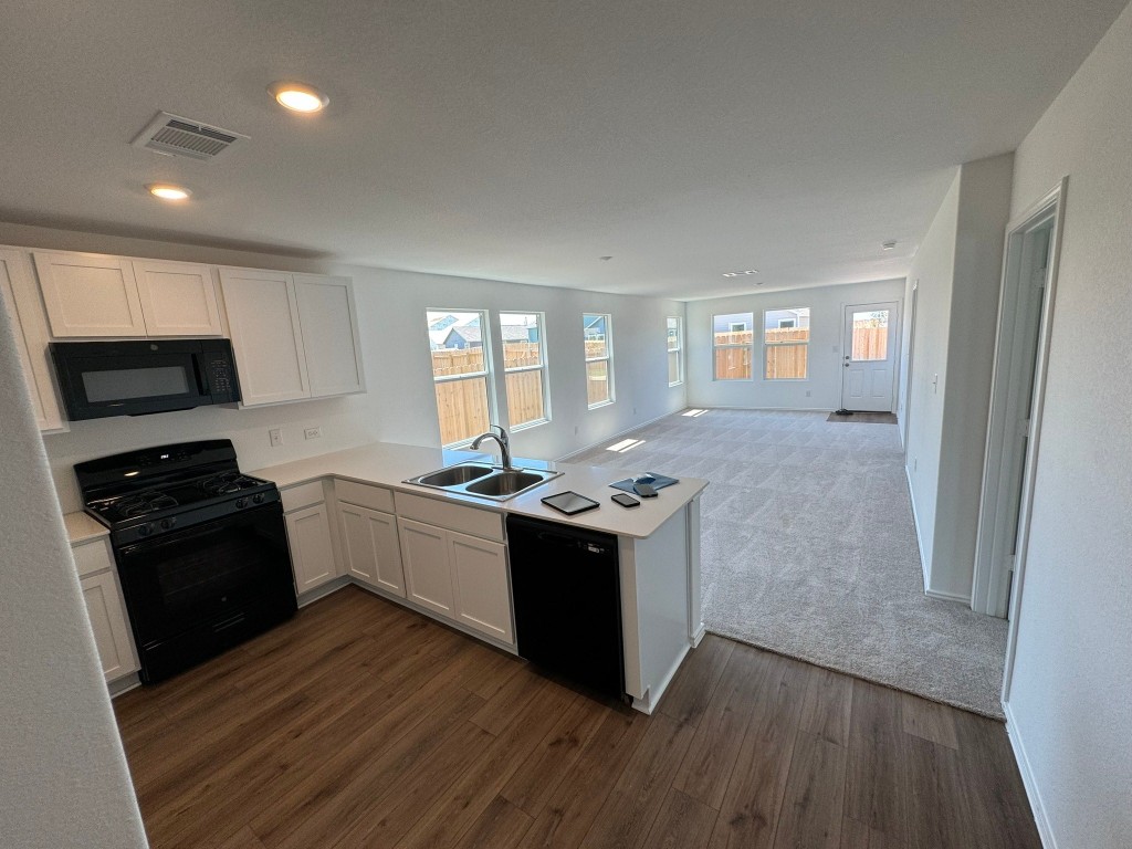 134 Avre Loop Kyle, TX 78640 - Photo 9 of 9 Kitchen featuring black appliances, light countertops, white cabinets, open floor plan, and recessed lighting