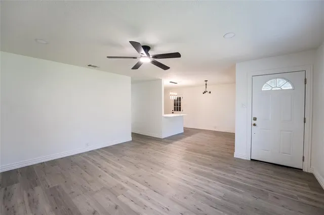 an empty room with wooden floor and ceiling fan