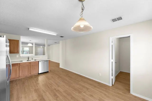 a large kitchen with a wooden floor and a refrigerator