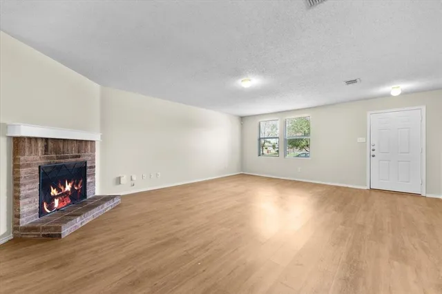 a view of an empty room with a fireplace and window