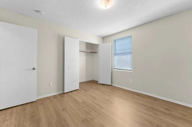 an empty room with wooden floor closet and windows