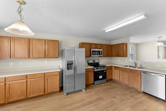 a kitchen with stainless steel appliances granite countertop a refrigerator a sink dishwasher a stove top oven a refrigerator with island and chairs