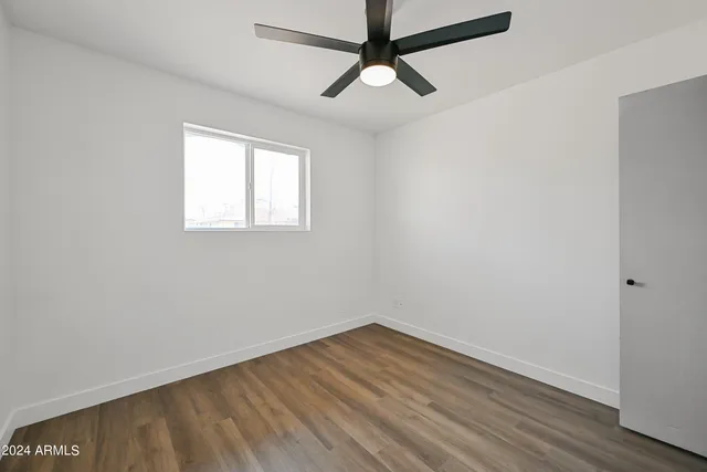an empty room with wooden floor fan and windows