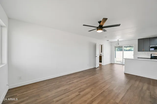 an empty room with wooden floor and a ceiling fan